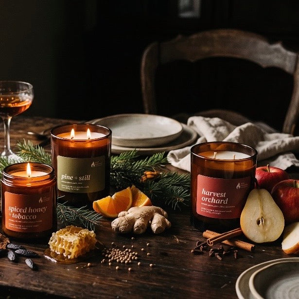 Pure Intentions fall candles gathered on a table with fruit, spices, and evergreen branches